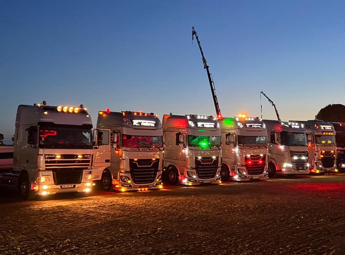 TC Ambree Fuhrpark bei Dämmerung: beleuchtete DAF-Zugmaschinen auf dem Betriebshof